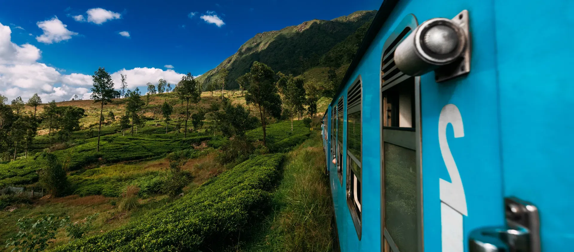Blue train traveling through Sri Lanka scenic hill country